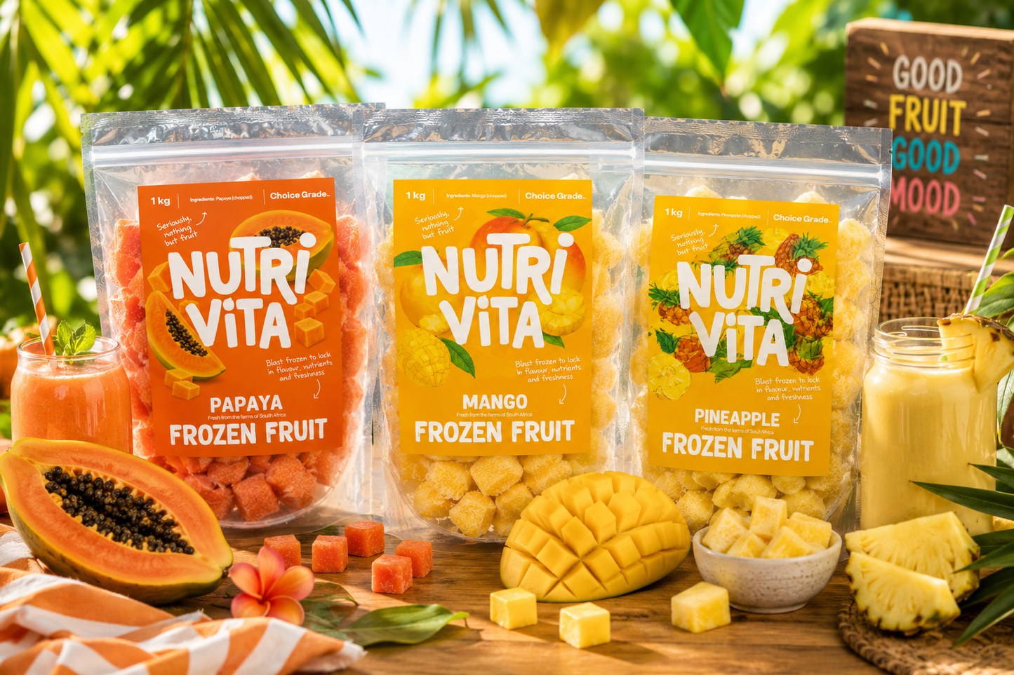 Three packages of NutriVita frozen fruit on a wooden table with fruits and drinks in the background.