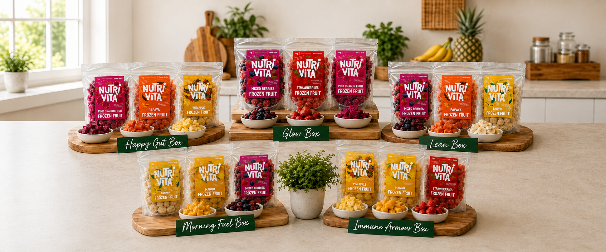 Four large clear display bins filled with assorted Nutri-Vita snack pouches, arranged on wooden trays on a kitchen counter. Visible flavors include Happy Gut Box, Glow Box, Morning Fuel Box, and Immune Armor Box, with additional smaller bags around them.
